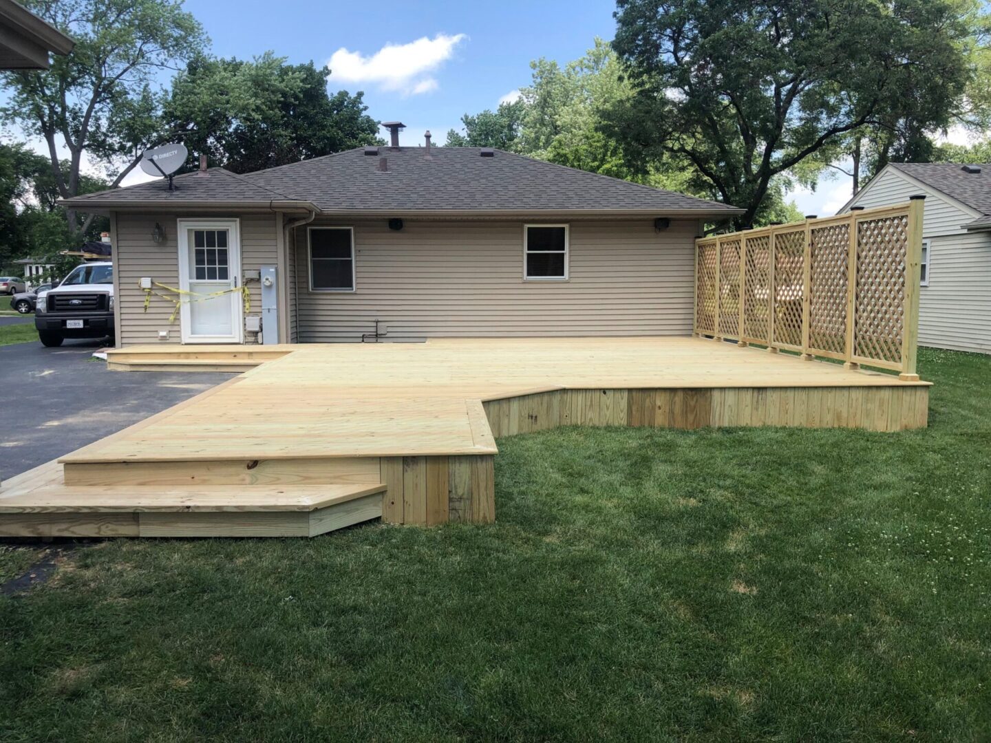 A backyard with a wooden deck and grass.