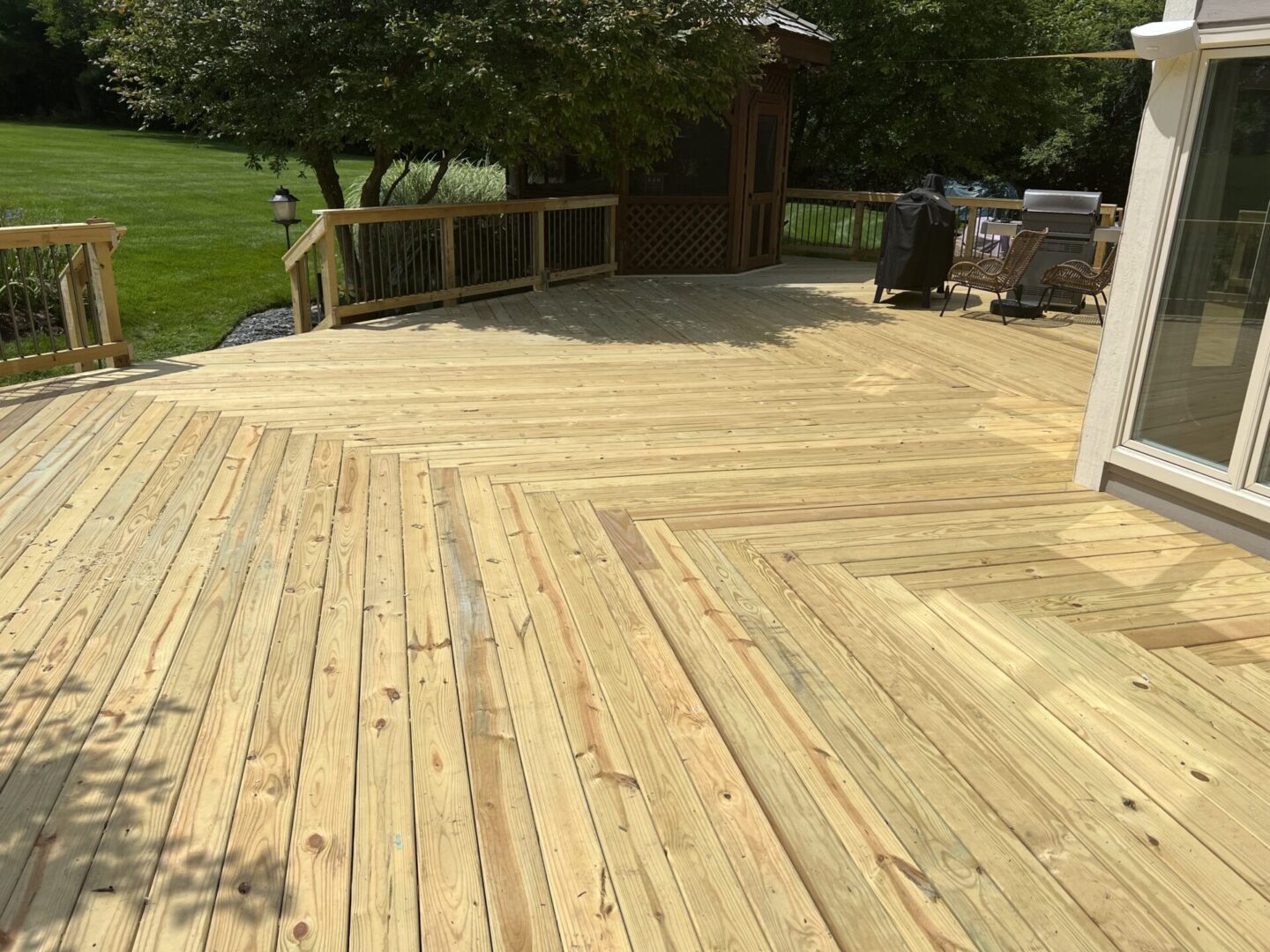 A wooden deck with a grill and table in the middle.