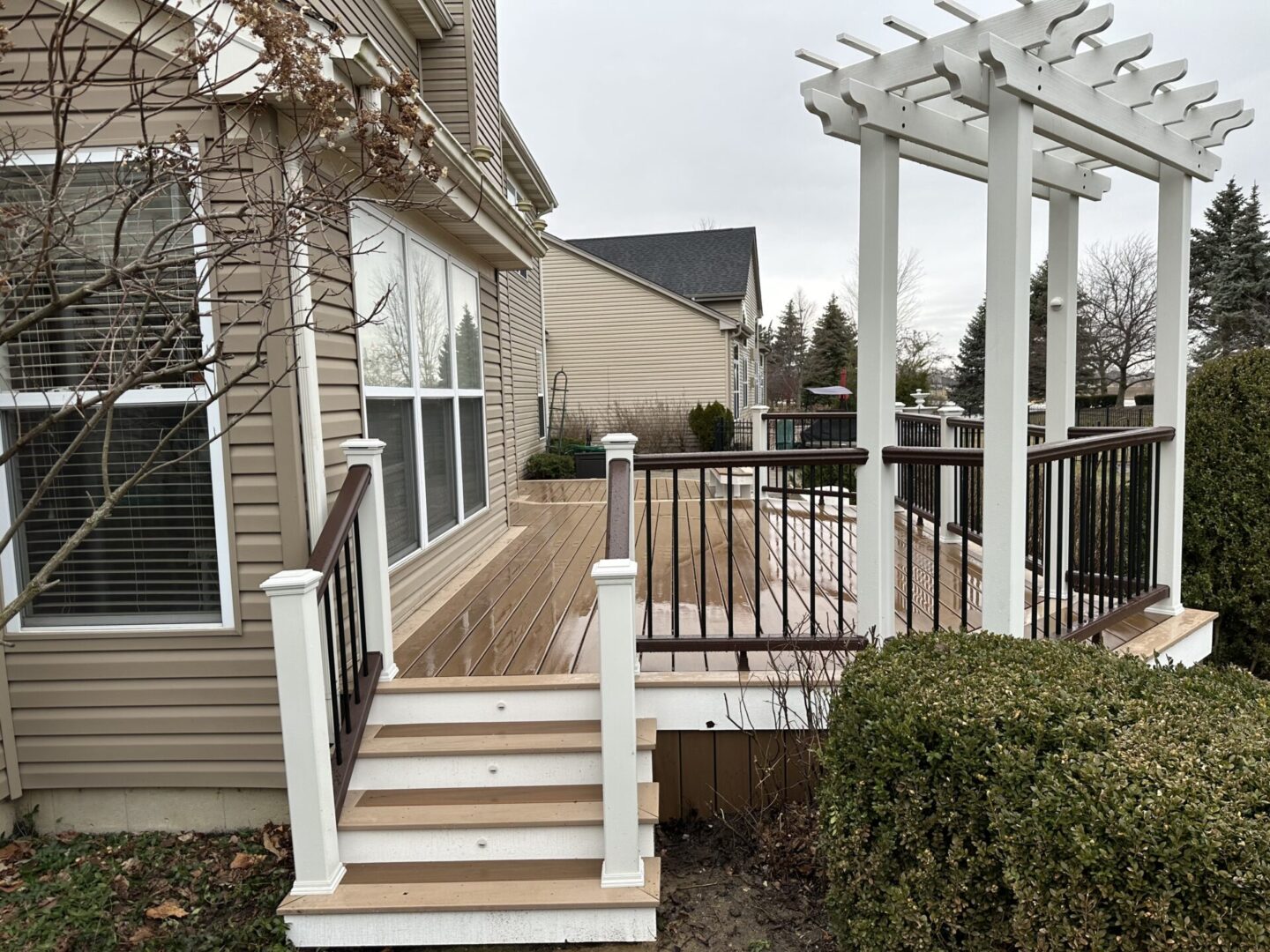 A deck with steps and a pergola in the background.