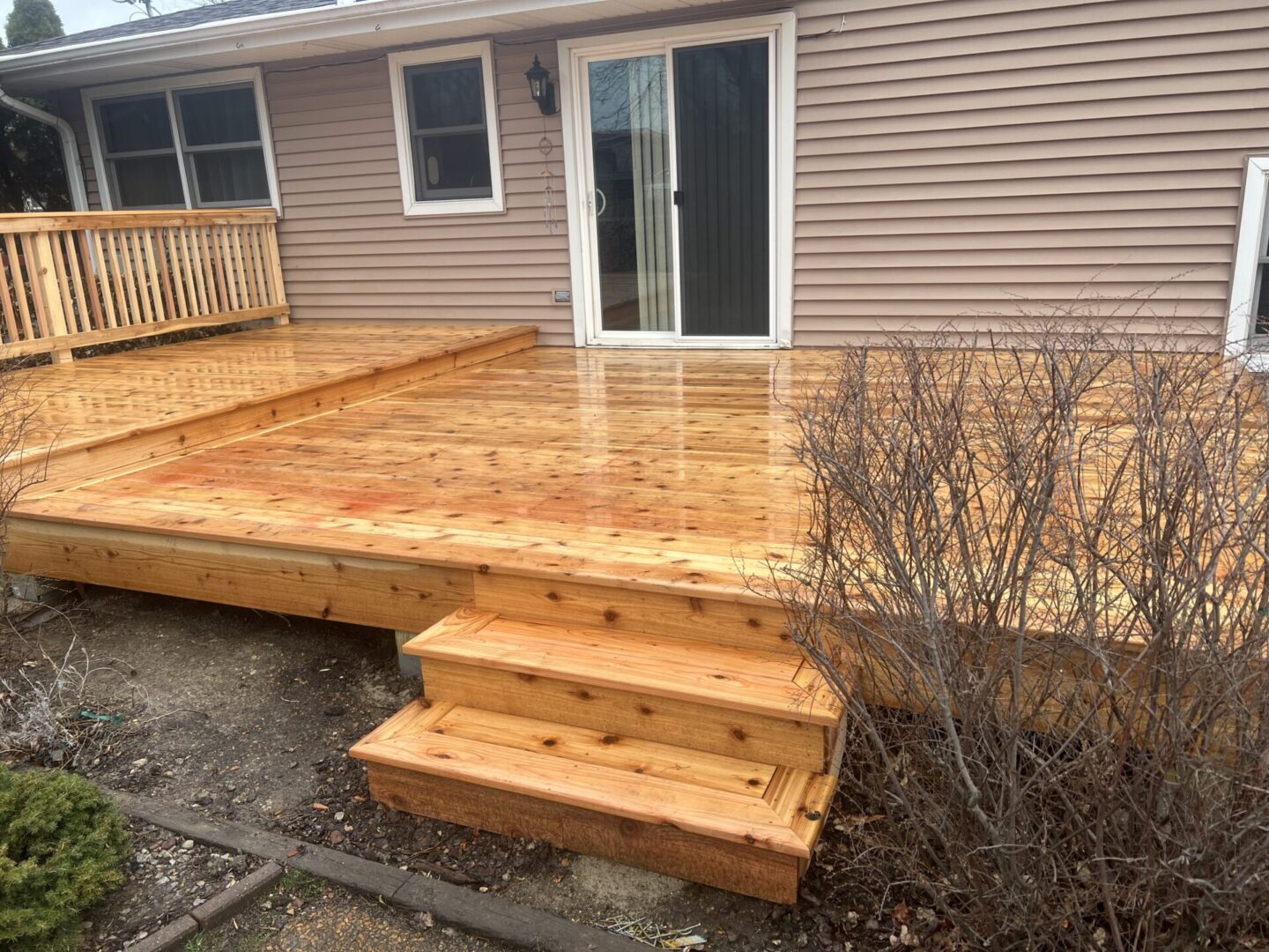 A wooden deck with steps leading to the back patio.